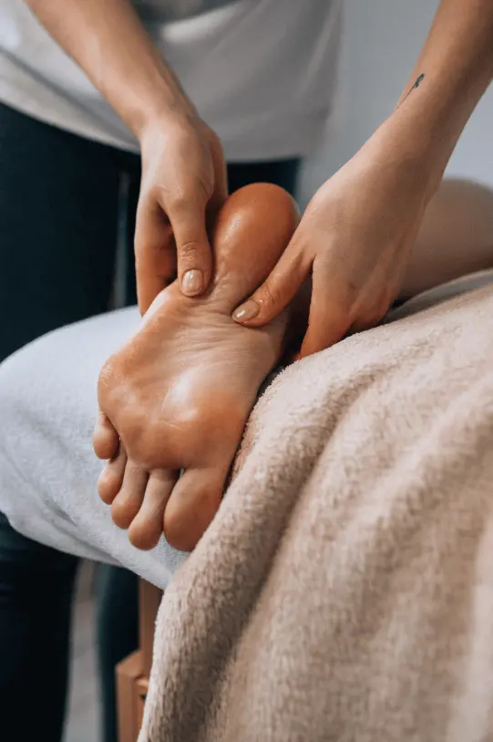 Therapist giving a relaxing foot massage to a client on a comfortable setup.